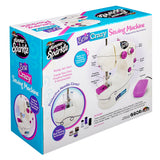 Shimmer 'N Sparkle Sew Crazy Sewing Machine: Safe Starter Tool for Young Fashionistas! box displaying features and accessories. Includes bobbins, thread, and more. Suitable for ages 8+. Primarily white with purple and blue design elements.