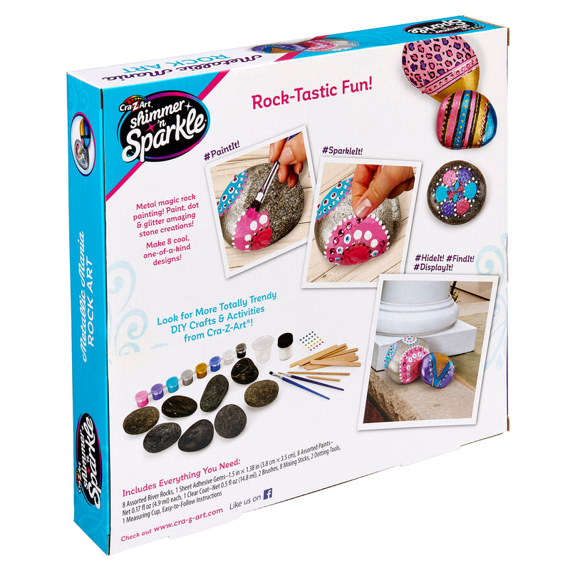The image shows a Cra-Z-Art Shimmer 'n Sparkle Metallic Mania Rock Art labeled "Rock-Tastic Fun!" The kit includes paint, brushes, rocks, and instructions to create decorative painted rocks. Examples of completed projects are shown on the box.