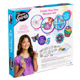 Box of "Shimmer 'n Sparkle Color Change Window Art" craft kit. The packaging features a smiling girl holding a completed design. The kit includes paints, stickers, design sheets, and instructions for making window art.