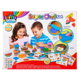 Two children playing with a Softee Dough Super Chef Set. The set includes dough, molds, tools, recipe cards, and mock food items in vibrant colors. Suitable for fun, creative kitchen play.