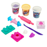 Softee Dough Donut Shop Medium box including three tubs of dough, a toy syringe, rolling pin, knife, mold, and components to create donuts are displayed on a white surface.