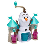 A Disney Frozen 2 Slushy Treat Maker featuring a snowman character surrounded by two castle towers with teal roofs and flags. The snowman has a lever on its head and is flanked by a pink and a purple cup at the base.