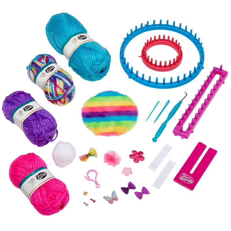 Various craft supplies including Shimmer 'n Sparkle 3 in 1 Ultimate Knitting Station, knitting looms, crochet hooks, a fuzzy pom-pom, decorative bows, buttons, and other small accessories arranged on a white background.