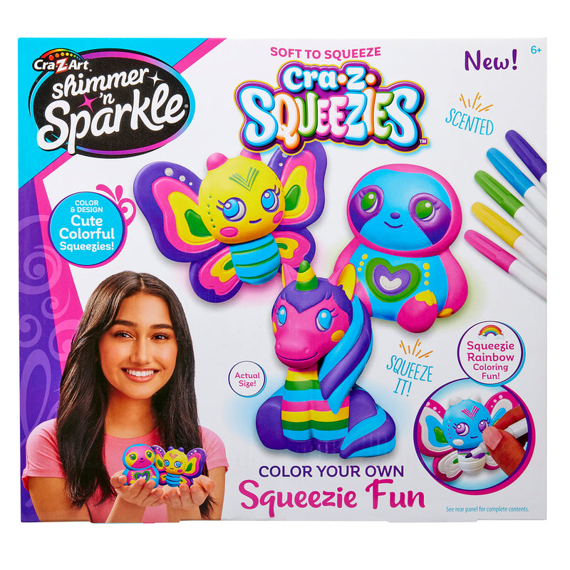 Product packaging for "Shimmer 'n Sparkle Cra-Z-Squeezies Color Your Own Squeezie Fun" showing colorful, squeezable toys and markers. The box features a girl holding the toys and highlights they are scented, soft to squeeze, and for ages 6 and up.