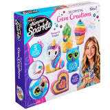 The image shows a Shimmer 'n Sparkle 3 D Crystal Gem Creations kit. The packaging features colorful gem-covered figures, including a unicorn, owl, and ice cream cone, with tools for crafting.