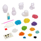 A Shimmer 'n Sparkle 3 D Crystal Gem Creations kit featuring bead art supplies, including white figurines, a bottle of glue, multi-colored beads, a glue pen, a tray, adhesive squares, and a pack of decorative eyes.