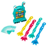 The Cra-Z-Art Monster Mash Board Game - Test your skills at matching! includes a teal animated monster figure, four spoon-like utensils in yellow, red, teal, and blue, and a deck of cards.