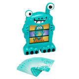 A Cra-Z-Art Monster Mash Board Game - Test your skills at matching! with googly eyes holds a card depicting a cartoon character. Several cards are spread in front of the board game.