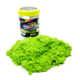 A container of Cra-Z Sand Glow sits behind a pile of green kinetic sand. The container label shows the weight of 1.5 lbs and the brand's logo.