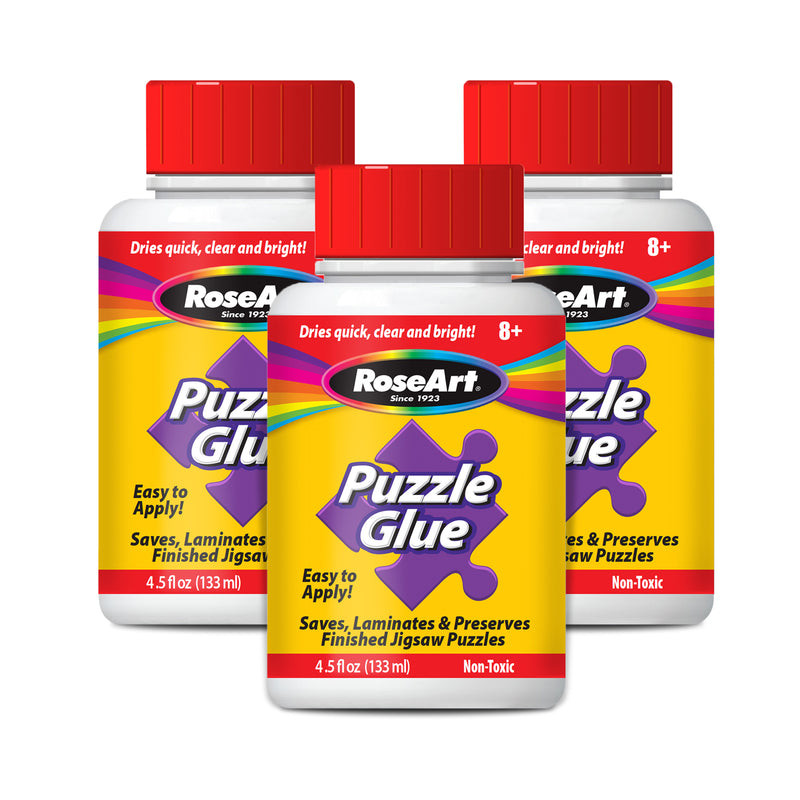 Three bottles of RoseArt - 4.5 oz Puzzle Glue 3 pack, each with a red lid and labeled as easy to apply, non-toxic, and suitable for ages 8 and up. The bottles contain 4.5 fl oz (133 ml) of glue.