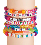 A close-up of a wrist wearing multiple Shimmer 'N Sparkle ABC Bead Bracelets with messages like #LOVE, UNICORN, #AMAZING, I ♥ U, and BESTIE.