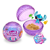 Inside the purple, crystal-shaped container of the Disney Crystal Surprise Color Change Ball, you'll find a color-changing ball accompanied by sand, a small blue alien figure wearing sunglasses, a palm tree, and an enigmatic gold item. The text prompts the captivating question: "What will you get?